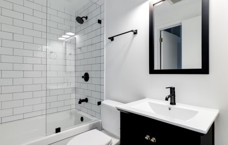 A bathroom with a black cabinet and subway tiles.